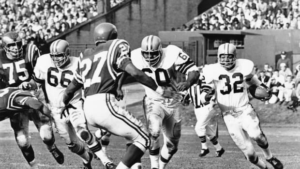 Cleveland Browns running back Jim Brown (32) carries the ball behind the blocking of John Wooten (60) and Gene Hickerson (66) against the Philadelphia Eagles defenders Irv Cross (27) and John Meyers (75) at Cleveland Municipal Stadium